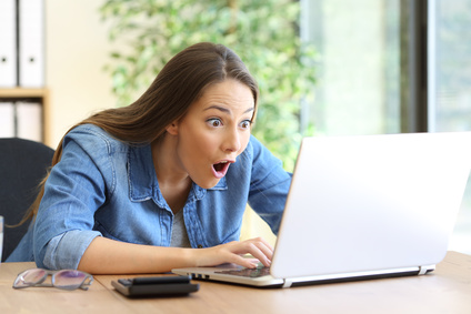 Frau sitzt nach Online-Bewerbung überrascht vor dem Laptop